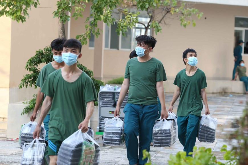 Los oficiales y soldados ayudan a llevar las porciones de comida a las áreas de tratamiento. (Foto: VNA)