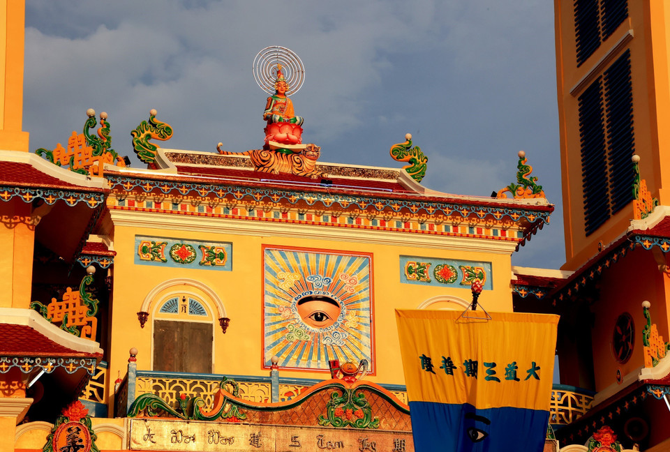 Una estatua de Buda sobre un loto y una escultura del Ojo Divino frente a la Santa Sede de Tay Ninh.