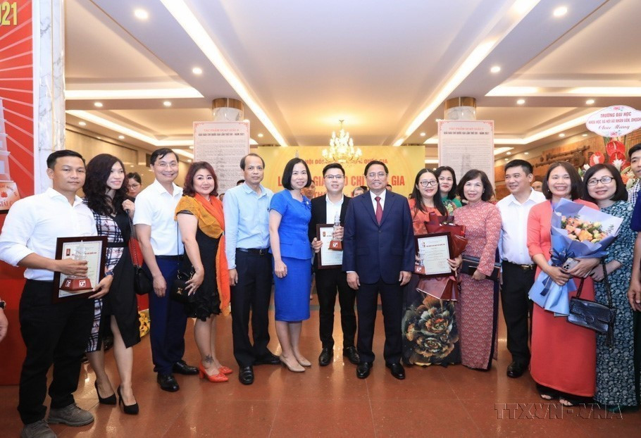 El primer ministro Pham Minh Chinh, la directora general Vu Viet Trang y los reporteros de VNA que ganaron el XVI edición del Premio Nacional de la Prensa - 2021. (Foto: VNA)