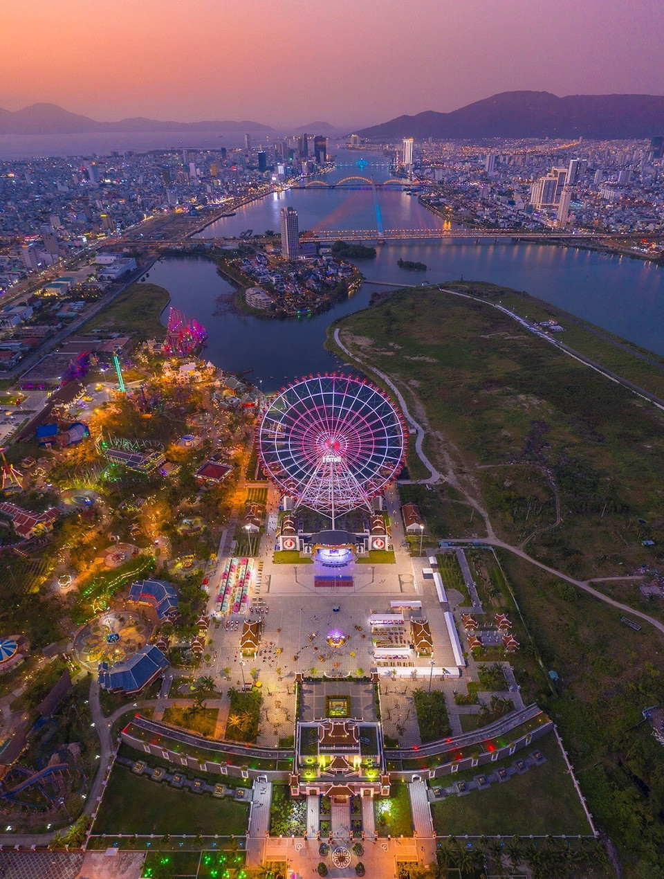 La foto desde arriba toma una vista panorámica de la fantástica urbe de Da Nang durante la puesta de sol, en la que destaca la rotación del sol en Asia Park, y en la distancia los puentes que cruzan el río Han.