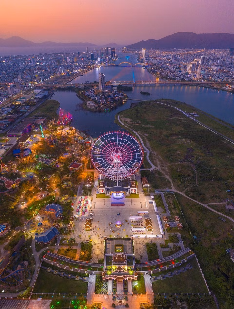 La foto desde arriba toma una vista panorámica de la fantástica urbe de Da Nang durante la puesta de sol, en la que destaca la rotación del sol en Asia Park, y en la distancia los puentes que cruzan el río Han.