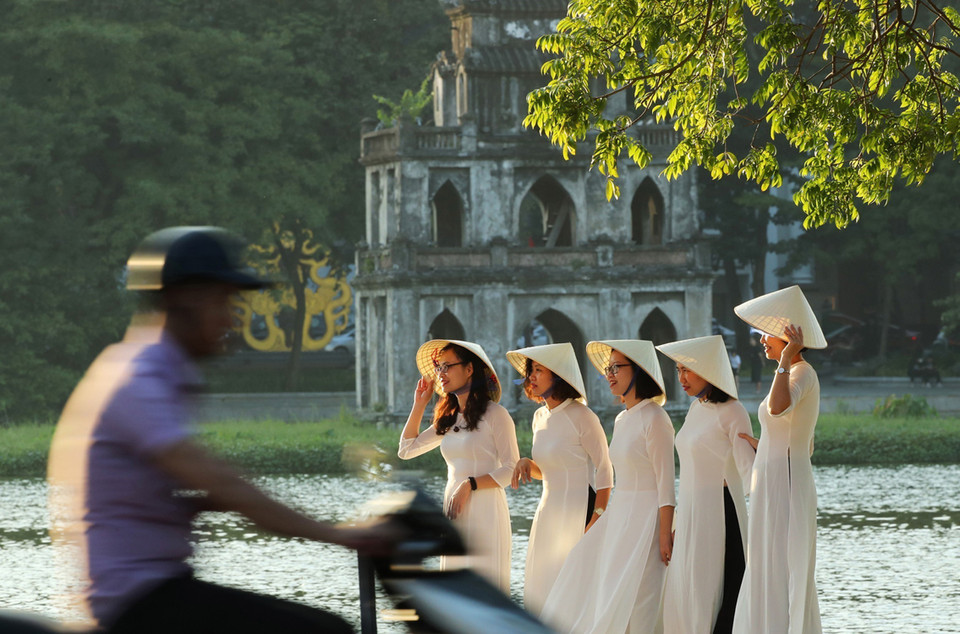 Jóvenes vestidas en Ao Dai (túnica tradicional vietnamita) posan para las fotos al atardecer en el lago Hoan Kiem (Foto: VNA)