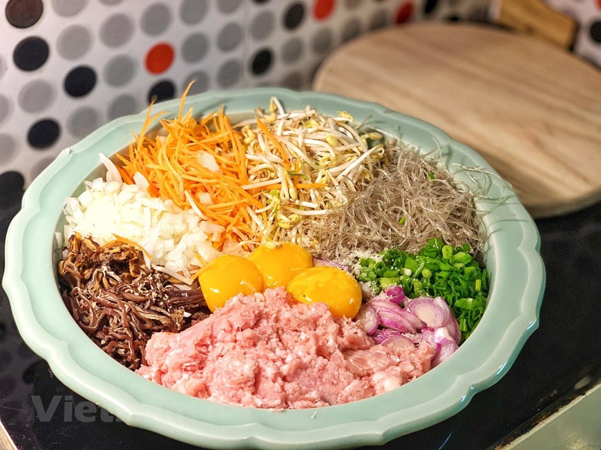 Remoje los fideos y hongos en agua caliente, y luego córtelos y mézclelos con otros ingredientes en un bol. (Foto: VNA)