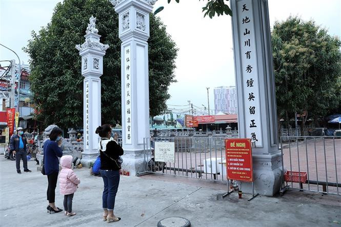 La gente reza a la entrada del templo Quan Thanh, pero utiliza mascarillas sanitarias y mantiene la distancia con otras personas (Foto: VNA)