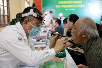 Un médico militar chino realiza chequeo a un poblador de la provincia de Lang Son (Foto: VNA)