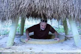 El turista se sitúa en una entrada de túnel ubicada en el jardín de una vivienda en el túnel de Ky Anh. (Fuente: VNA)