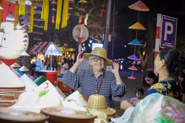 Una visitante internacional queda encantada con los productos tradicionales vietnamitas en el Festival de Regalos Turísticos de Hanoi 2025. (Fuente: VNA)