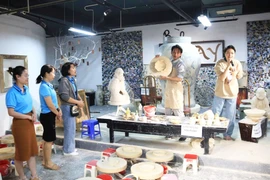 Turistas observan una exhibición de cerámica tradicional en la aldea artesanal de Bat Trang. (Fuente: hanoimoi.vn)