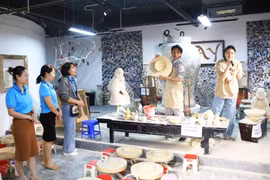 Turistas observan una exhibición de cerámica tradicional en la aldea artesanal de Bat Trang. (Fuente: hanoimoi.vn)
