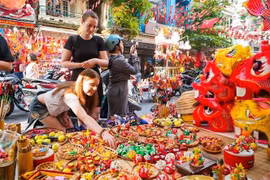 Las turistas extranjeras están interesadas ​​en conocer sobre los juguetes tradicionales vietnamitas del Festival del Medio Otoño. (Fuente: VNA)