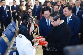 El primer ministro vietnamita, Pham Minh Chinh, entrega dinero de la suerte a los pasajeros en la estación de tren de Hanoi. (Fuente: VNA)