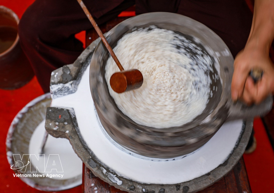 Proceso de molienda el arroz con un molino de piedra tradicional. (Foto: VNA)