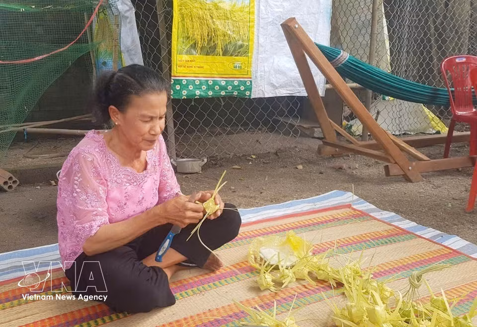 La artesana Néang Phuong teje meticulosamente cada envoltura del pastel, mostrando la habilidad y delicadeza de las mujeres khmer. (Foto: VNA)