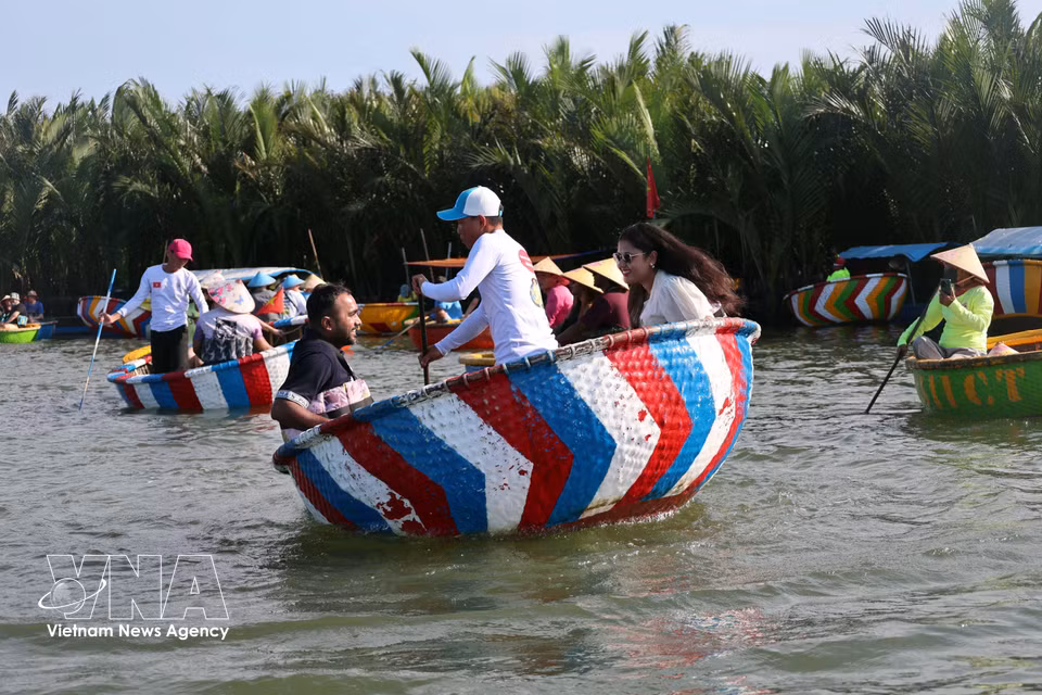 Turistas internacionales prueban la técnica tradicional de “hacer girar la barca de cesta”, practicada por los habitantes locales en la aldea de cocoteros de Cam Thanh, uno de los 50 pueblos más bellos del mundo en 2025. Foto: VNA