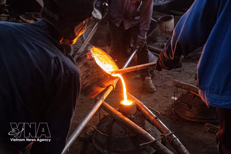 El metal fundido se vierte en el molde. Esta etapa requiere la coordinación de varias personas y exige alta precisión técnica. (Foto: VNA)
