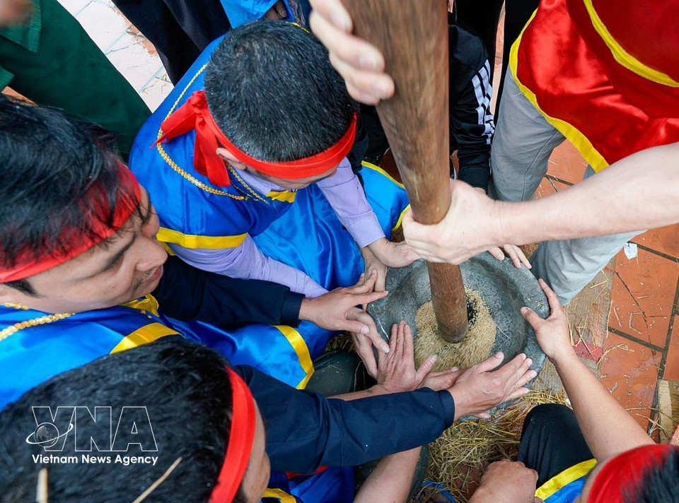 Jóvenes del equipo machacan el arroz en morteros de piedra. (Foto: VNA)