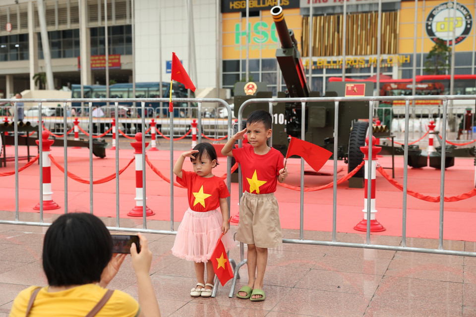 Los padres permiten a sus niños portar la bandera nacional para tomarse fotos con la artillería ceremonial. Foto: VNA