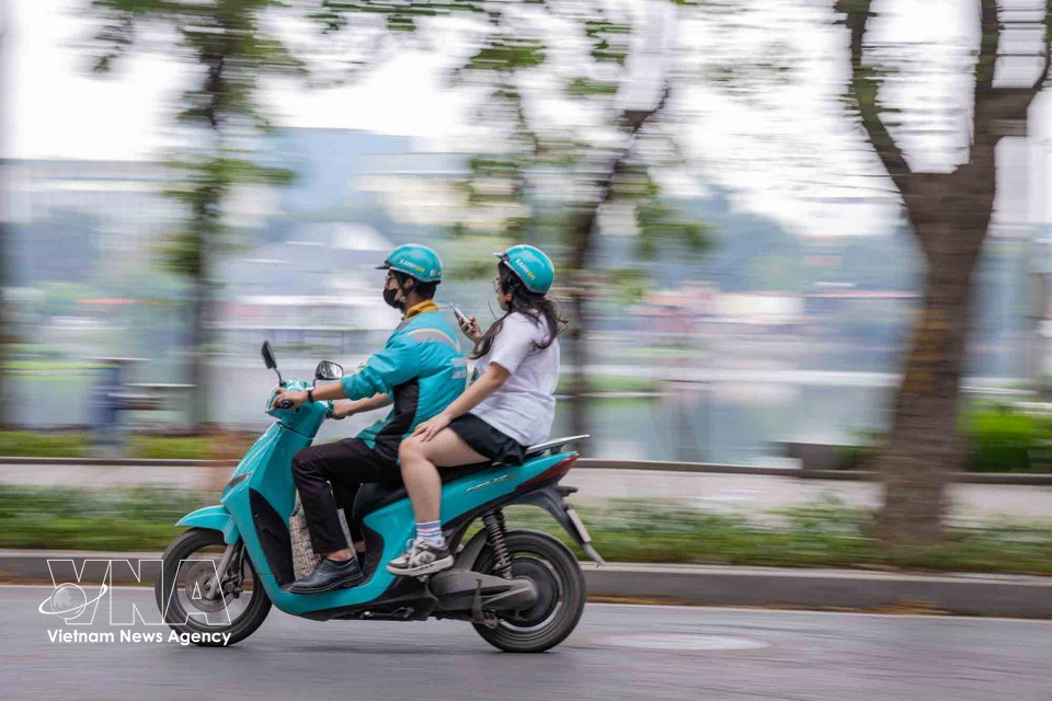Un conductor de transporte mediante aplicación utiliza una motocicleta eléctrica para trasladar pasajeros en la calle Nguyen Du, en Hanoi. (Foto: VNA)