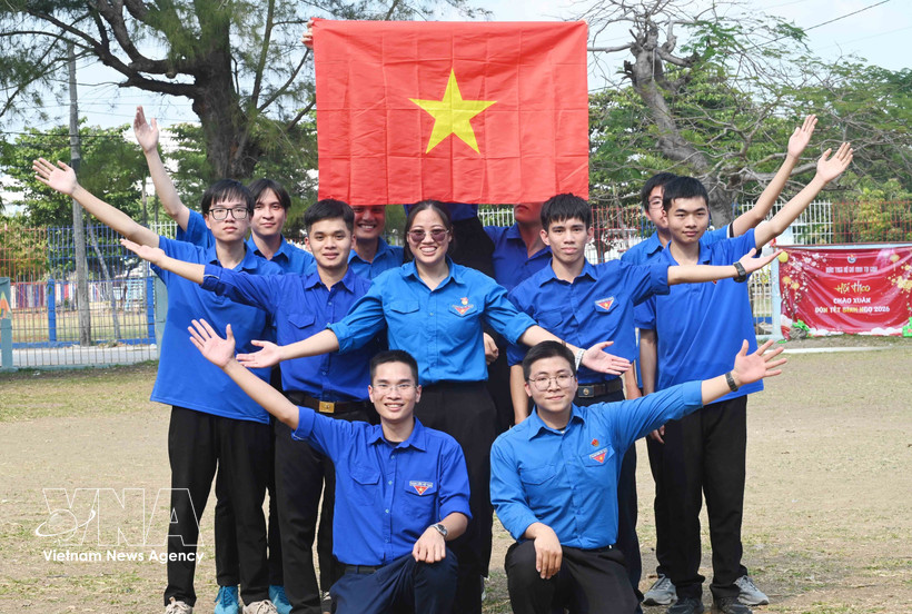 Miembros de la Unión de Jóvenes Comunistas Ho Chi Minh en Cuba izan la bandera nacional. Foto: VNA