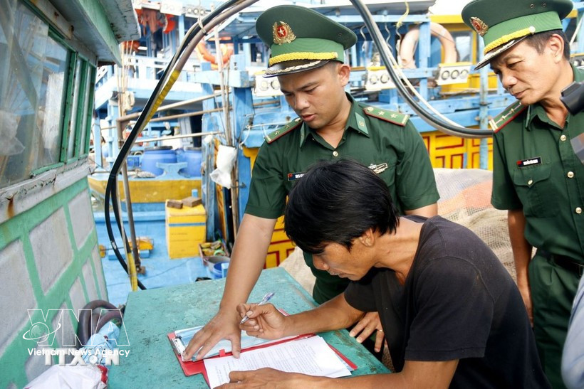 Oficiales de la Guardia Fronteriza guían a los pescadores en la firma de un compromiso de no infringir las normas de pesca IUU. (Foto: VNA)
