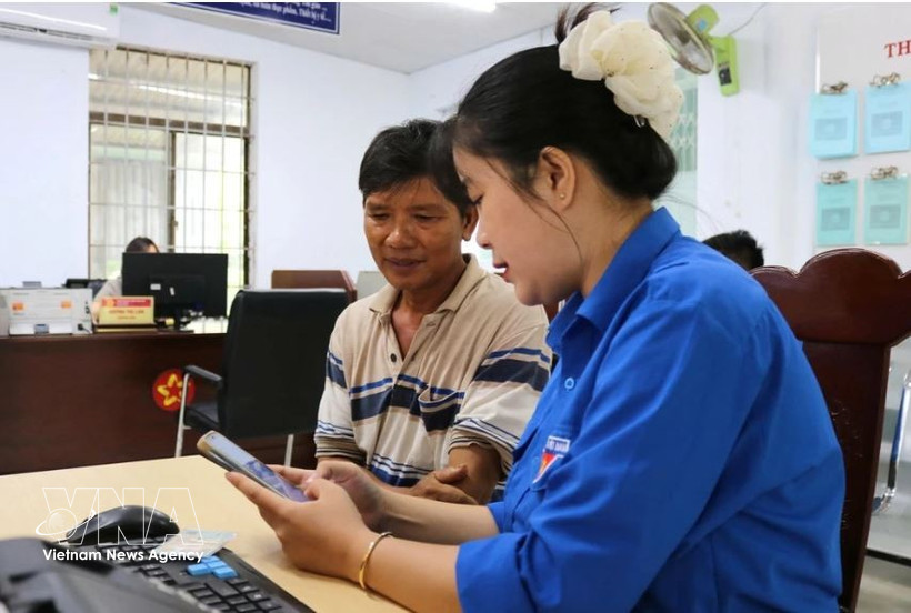 Una jóven de la Unión de Jóvenes Comunistas Ho Chi Minh de la comuna de Tuy An Nam, provincia de Dak Lak, orienta a los residentes sobre cómo completar la información correctamente antes de presentar los documentos para trámites administrativos. Foto: VNA