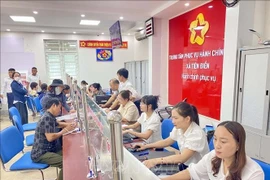 Funcionarios y ciudadanos realizan trámites administrativos en el centro de servicios administrativos públicos de la comuna de Tien Dien, provincia de Ha Tinh. (Foto: VNA)
