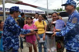 Un oficial de la delegación de la Guardia Costera de Vietnam presenta porciones de comida a los residentes afectados por el terremoto en la provincia de Bogo, Filipinas. (Foto: nhandan.vn)