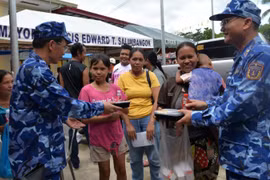 Un oficial de la delegación de la Guardia Costera de Vietnam presenta porciones de comida a los residentes afectados por el terremoto en la provincia de Bogo, Filipinas. (Foto: nhandan.vn)