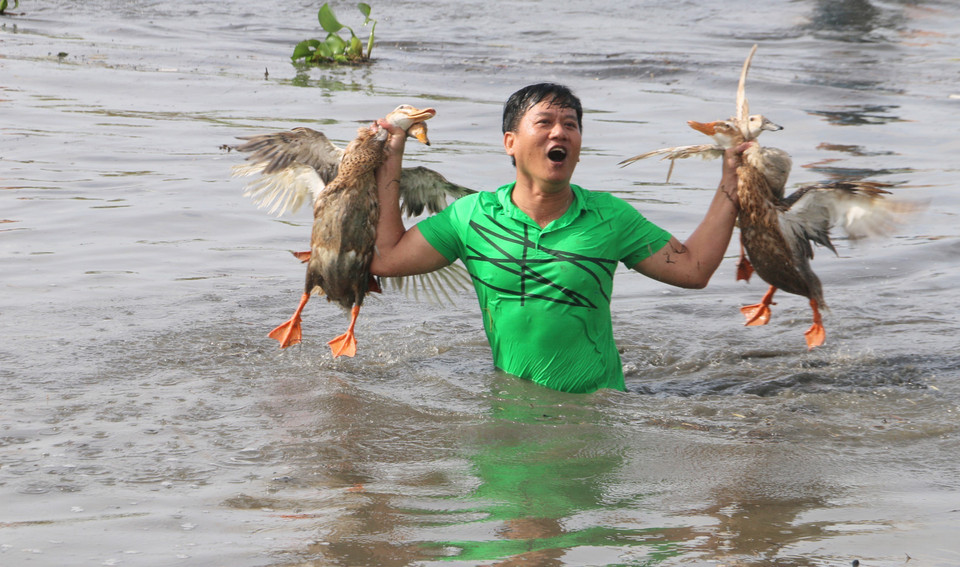 La alegría de los participantes al mostrar los “logros” obtenidos tras competir en el juego folclórico de atrapar patos en el agua. Foto: VNA