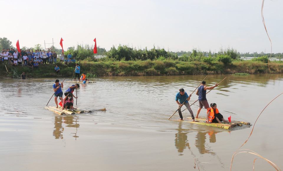 Habitantes y visitantes participan en el juego tradicional de remar en balsas de troncos de plátano para llevar a los soldados a través del río. Foto: VNA