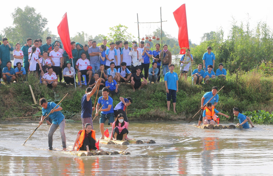 Habitantes y visitantes participan en el juego tradicional de remar en balsas de troncos de plátano para llevar a los soldados a través del río. Foto: VNA
