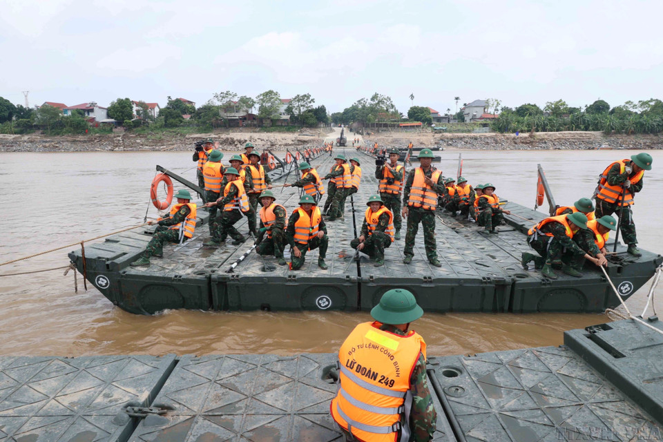 Las fuerzas de ingenieros de la Brigada 249 culminan el ensamblaje del puente flotante para facilitar el cruce del río a la población, tras el colapso del antiguo puente Phong Chau por las lluvias e inundaciones. Foto: VNA
