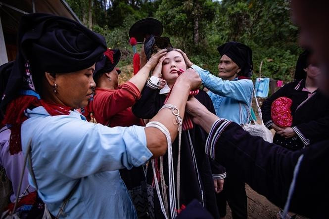 Las mujeres mayores, tías y hermanas visten a la novia con múltiples capas de trajes tradicionales. Foto: VNA