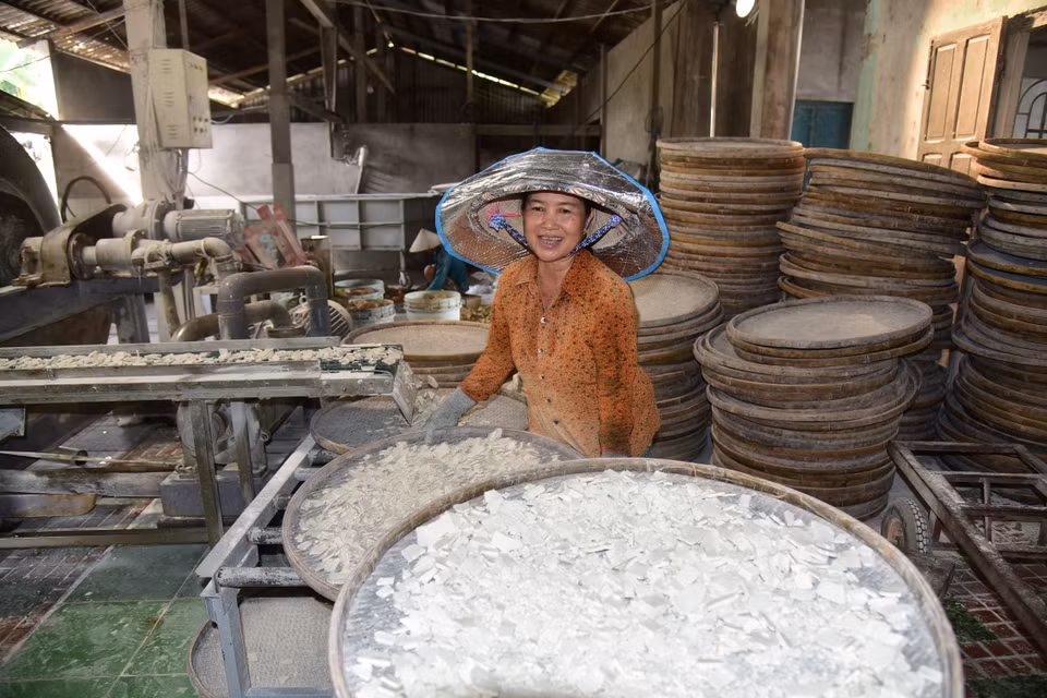 Huynh Thi Hong Nga vierte la harina en bandejas de bambú, la extiende uniformemente y luego la pone a secar al sol. Foto: VNA