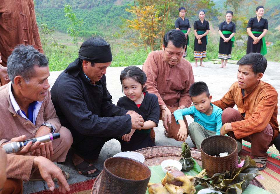 Los niños son atados con hilos en las muñecas por el chamán, los ancianos, jefes de aldea y personas de prestigio, y se les asigna oficialmente un apellido y nombre tras finalizar el ritual de bendición para la aldea. Foto: VNA