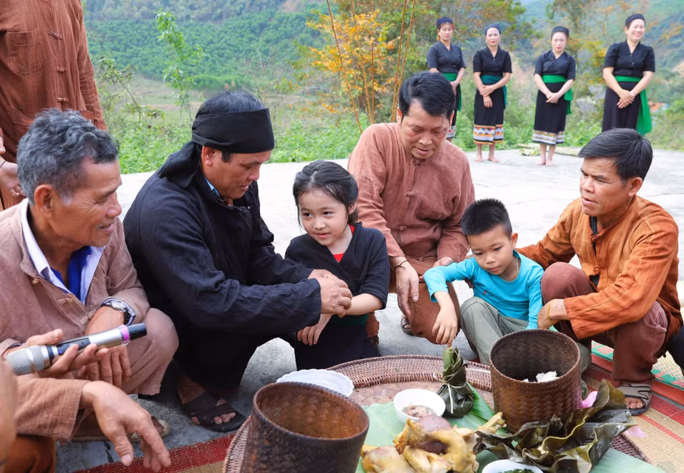 Los niños son atados con hilos en las muñecas por el chamán, los ancianos, jefes de aldea y personas de prestigio, y se les asigna oficialmente un apellido y nombre tras finalizar el ritual de bendición para la aldea. Foto: VNA