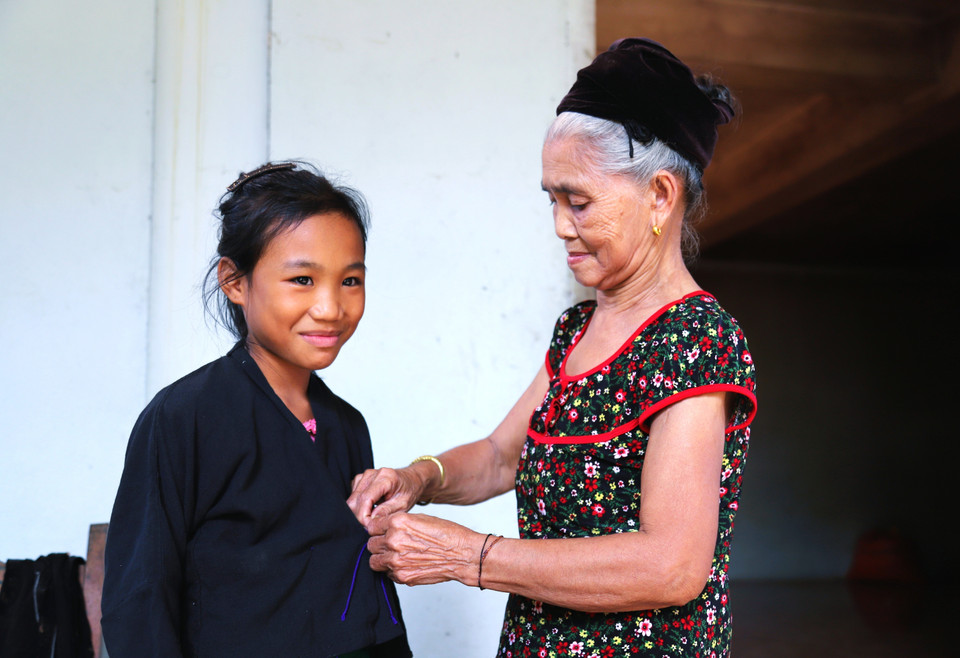 Los niños O'du aprenden de los adultos cómo vestir el traje tradicional antes de participar en la ceremonia del primer trueno, el ritual de atado de hilos en la muñeca y la ceremonia de nombramiento. Foto: VNA
