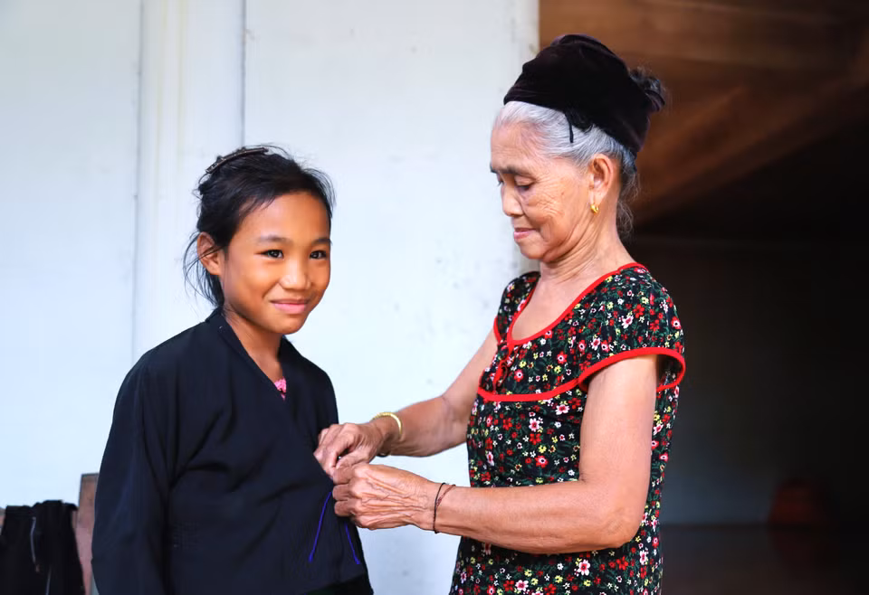 Los niños O'du aprenden de los adultos cómo vestir el traje tradicional antes de participar en la ceremonia del primer trueno, el ritual de atado de hilos en la muñeca y la ceremonia de nombramiento. Foto: VNA