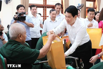 El presidente Luong Cuong entrega obsequios a Nguyen Xuan Mai, inválido de guerra, quien recibe tratamiento en el Centro de Rehabilitación de Veteranos de Guerra de Duy Tien. (Foto: VNA)