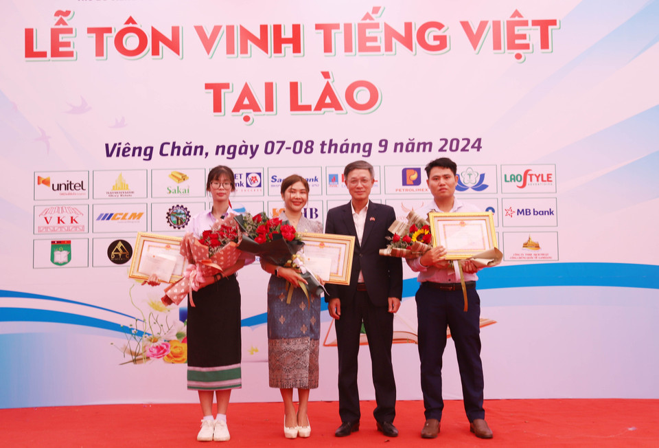 El encargado de negocios de Vietnam en Laos, Phan Minh Chien, entrega certificados de mérito y premios a tres concursantes que participan en la ronda final del concurso "En busca de embajadores vietnamitas en el extranjero en 2024". (Fuente: VNA)