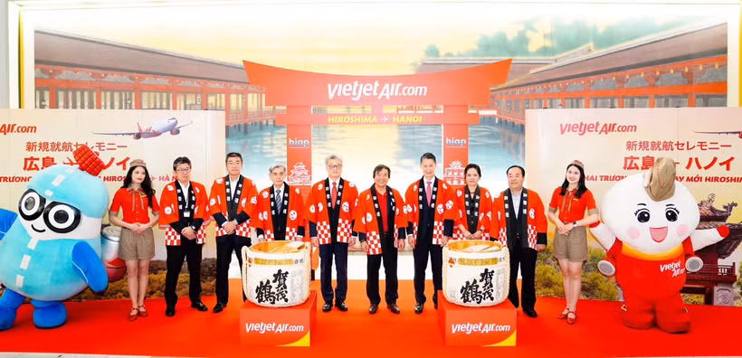 La cónsul general de Vietnam en Fukuoka Vu Chi Mai (tercera de la derecha), el gobernador de la prefectura de Hiroshima Yuzaki Hidehiko (cuarto de la derecha), el director general adjunto de Vietjet, Nguyen Duc Thinh (quinto de la derecha) y el presidente y director representante del Aeropuerto Internacional de Hiroshima, Yasuhiro Nakamura (quinto de la izquierda) junto con otros delegados en el escenario en la ceremonia para lanzar el primer vuelo que conecta Hiroshima y Hanoi. (Fuente: Vietjet)