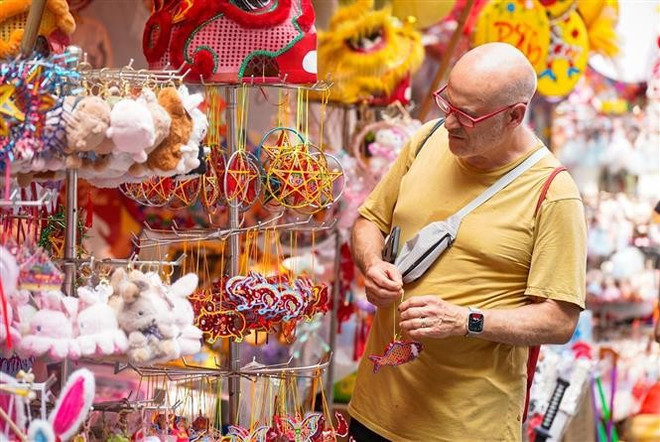 Un turista extranjero elige artículos del Festival del Medio Otoño en la calle Hang Ma. (Fuente: VNA) choi.jpg