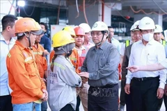 El primer ministro Pham Minh Chinh (segundo desde la derecha) felicita por el Año Nuevo a los trabajadores de la obra de construcción de la Terminal 3 del Aeropuerto Internacional de Tan Son Nhat en Ciudad Ho Chi Minh. (Foto: VNA)