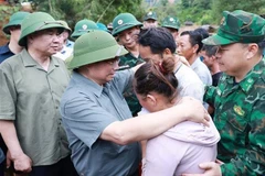 El primer ministro Pham Minh Chinh consuela a una familia cuyo miembro falleció en las recientes inundaciones en la comuna de Xa Dung. (Foto: VNA)