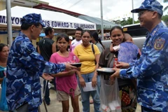 Un oficial de la delegación de la Guardia Costera de Vietnam presenta porciones de comida a los residentes afectados por el terremoto en la provincia de Bogo, Filipinas. (Foto: nhandan.vn)