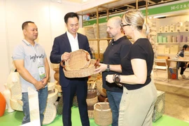 Clientes internacionales aprenden sobre los productos artesanales vietnamitas. (Fuente: VNA)