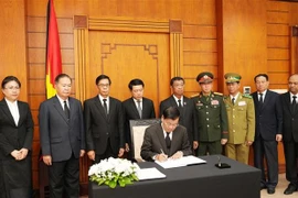 El secretario general del Partido Popular Revolucionario de Laos y presidente del país, Thongloun Sisoulith, escribe en el libro de condolencias. (Fuente: VNA)