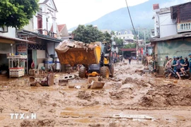 Se movilizaron excavadoras para nivelar y recoger el lodo, las ramas de árboles y la basura arrastrada por la reciente inundación en la comuna de Song Ma, provincia de Son La. (Foto: VNA)