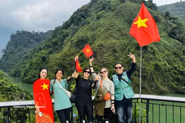 Turistas extranjeros se fotografían con entusiasmo junto a lugareños que visten trajes tradicionales adornados con la bandera roja y la estrella amarilla. (Foto: VNA)