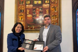 El diputado Víctor Aldaya entrega a la embajadora de Vietnam en Aregentina, Ngo Minh Nguyet, un juego de sellos emitidos por Correos del Uruguay en diciembre de 2013, en conmemoración del 20.º aniversario de las relaciones diplomáticas entre Vietnam y Uruguay, con el retrato del General Vo Nguyen Giap. (Fuente: VNA)